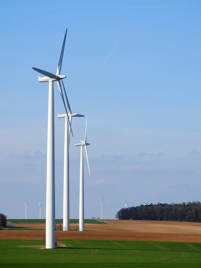 about-05 Row of wind turbines in a rural area, generating renewable energy under a blue sky.