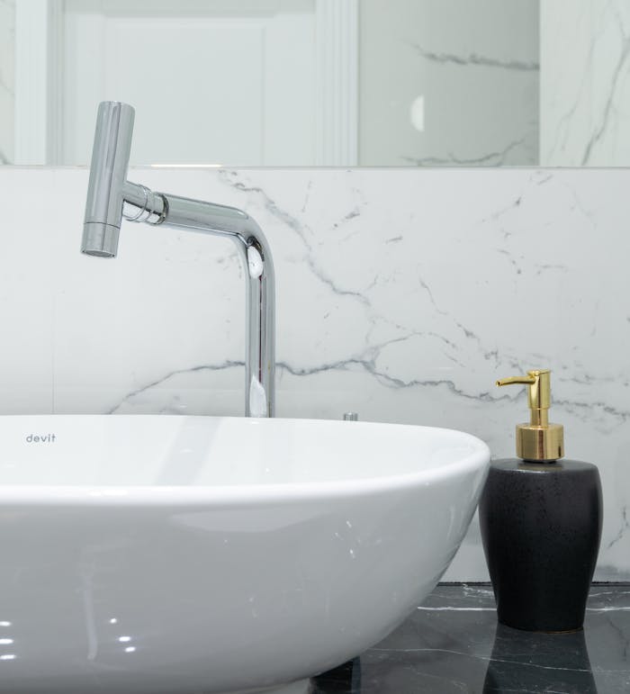 about-07 Stylish bathroom featuring a modern chrome faucet, marble backsplash, and a white ceramic washbasin.